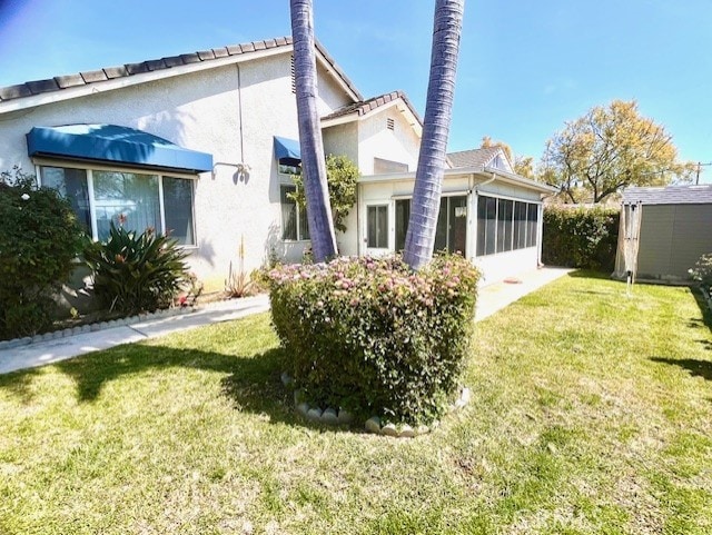 11950 Reichling Ln, Whittier, CA 90606 - back of property with stucco siding, a storage shed, an outbuilding, a yard, and a sunroom