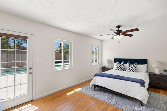 bedroom with access to outside, a textured ceiling, a ceiling fan, baseboards, and hardwood / wood-style flooring