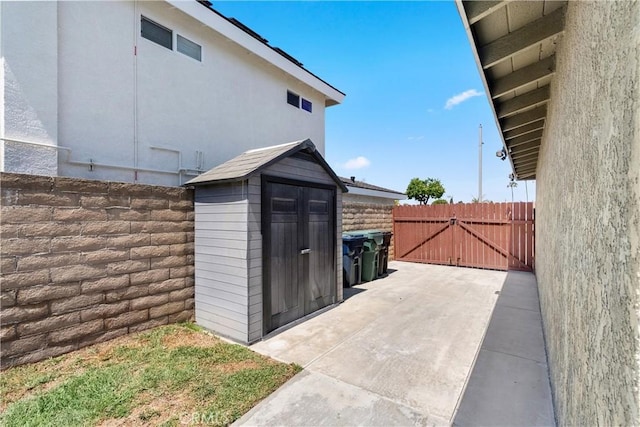 view of shed featuring fence and a gate