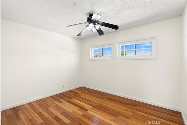 spare room featuring a textured ceiling, baseboards, a ceiling fan, and wood finished floors