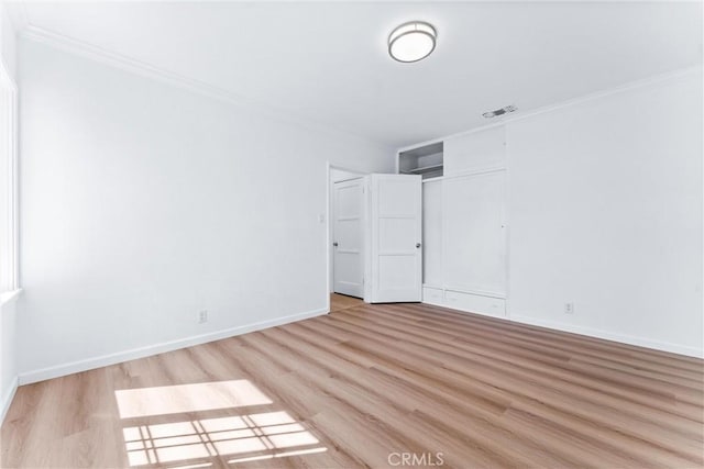 spare room featuring baseboards, wood finished floors, and ornamental molding