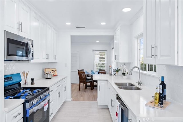 kitchen with a sink, stainless steel appliances, light countertops, white cabinets, and visible vents