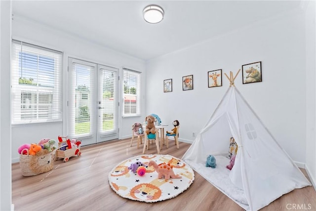 recreation room featuring baseboards, crown molding, french doors, and wood finished floors