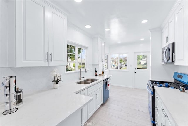 kitchen with a sink, decorative backsplash, light countertops, white cabinets, and appliances with stainless steel finishes