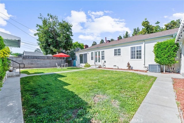 back of property with a chimney, fence, cooling unit, stucco siding, and a lawn