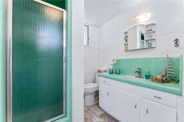 bathroom with tile walls, vanity, toilet, and a stall shower