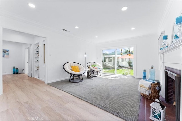 sitting room featuring wood finished floors, a fireplace, ornamental molding, visible vents, and recessed lighting