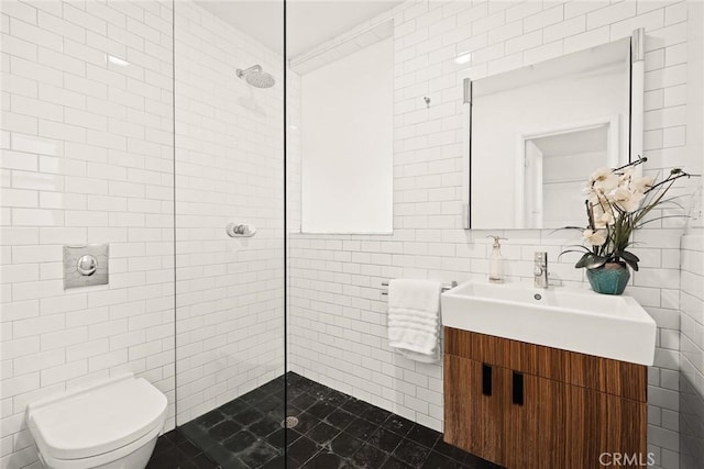 full bathroom with tiled shower, vanity, tile walls, and toilet