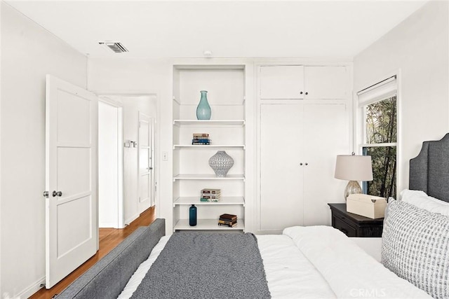 bedroom featuring a closet, wood finished floors, and visible vents