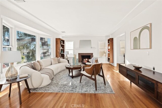 living area with wood finished floors, a fireplace, and visible vents