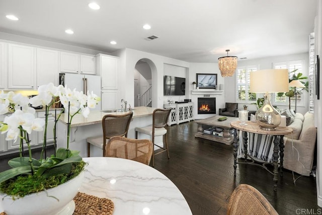 3477 Filoli Cir, Carlsbad, CA 92009 - living room with arched walkways, dark wood-type flooring, recessed lighting, and a warm lit fireplace