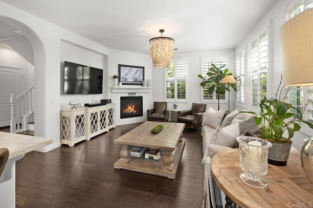 3477 Filoli Cir, Carlsbad, CA 92009 - living room featuring dark wood finished floors, a glass covered fireplace, arched walkways, a chandelier, and stairs