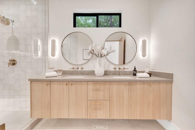 bathroom featuring tiled shower, double vanity, and a sink