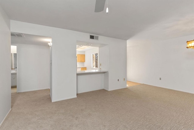 unfurnished living room with visible vents, ceiling fan, light colored carpet, and baseboards
