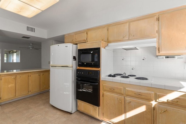 kitchen featuring backsplash, under cabinet range hood, visible vents, tile countertops, and black appliances