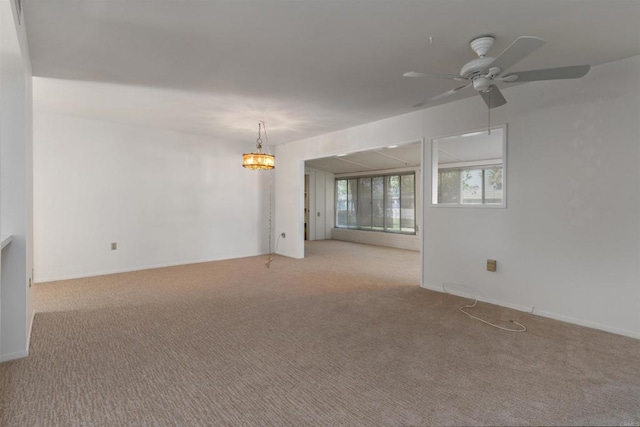 spare room featuring baseboards, carpet, and ceiling fan with notable chandelier