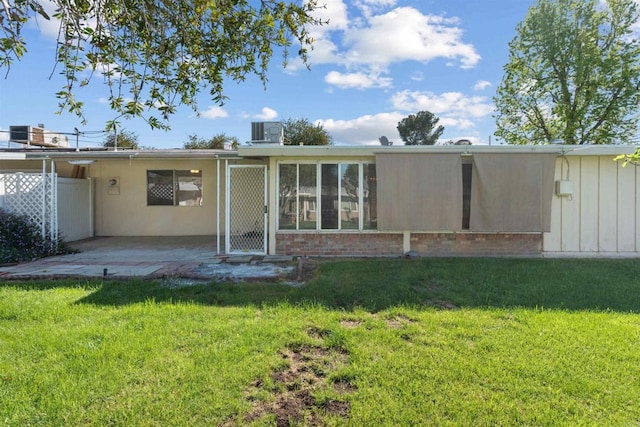 rear view of property featuring a yard, a patio, and fence