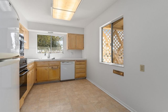 kitchen with baseboards, a sink, white appliances, tile counters, and decorative backsplash