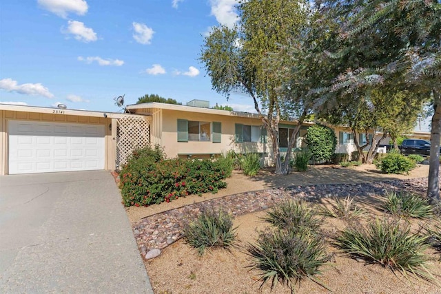ranch-style home featuring an attached garage, driveway, and stucco siding