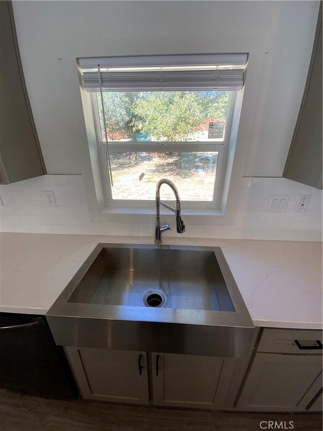 details featuring tasteful backsplash, a sink, and light stone counters