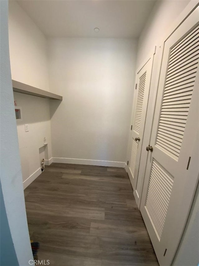 clothes washing area with dark wood-type flooring, laundry area, and baseboards