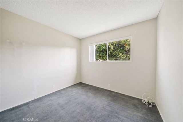 empty room with baseboards, dark colored carpet, and a textured ceiling