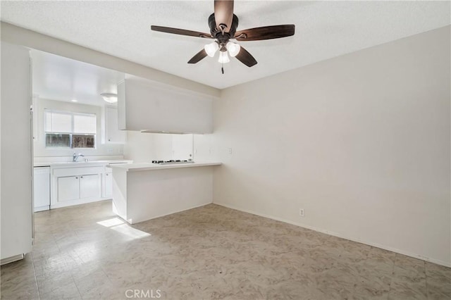 interior space featuring a sink, light countertops, ceiling fan, a peninsula, and white cabinetry