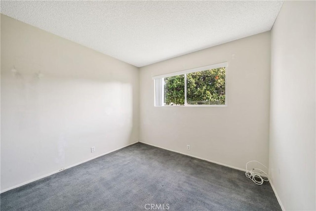 spare room featuring dark carpet, baseboards, and a textured ceiling