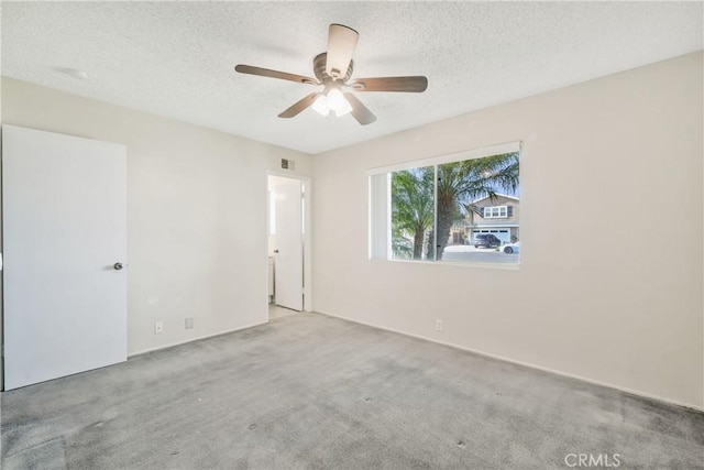 carpeted spare room with visible vents, ceiling fan, and a textured ceiling