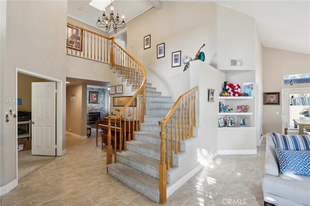 stairway with high vaulted ceiling, an inviting chandelier, and baseboards