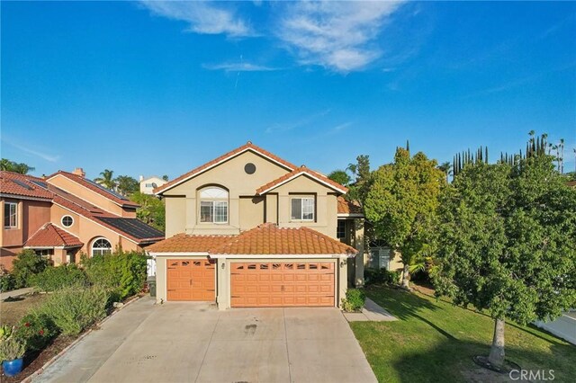 mediterranean / spanish-style house featuring concrete driveway, a tiled roof, a front lawn, and stucco siding