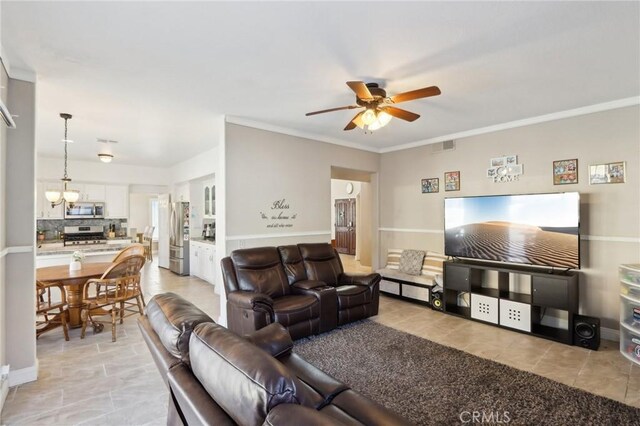 living area featuring light tile patterned floors, crown molding, visible vents, and ceiling fan with notable chandelier
