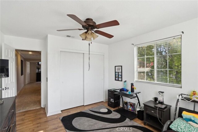bedroom with a closet, wood finished floors, visible vents, and a ceiling fan