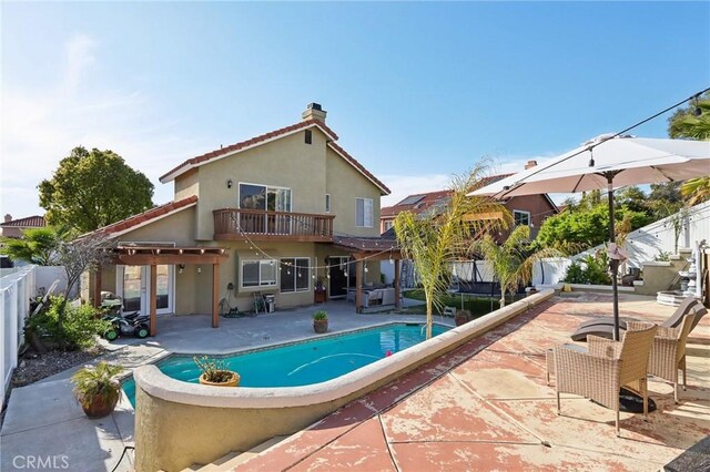 rear view of house with a patio area, a chimney, a fenced backyard, a fenced in pool, and stucco siding