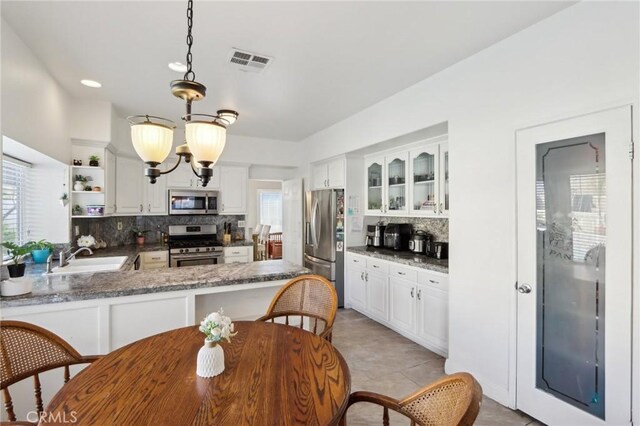 kitchen featuring tasteful backsplash, open shelves, a sink, appliances with stainless steel finishes, and visible vents