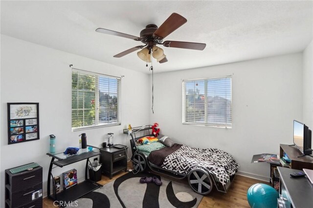 bedroom with baseboards, a ceiling fan, and wood finished floors