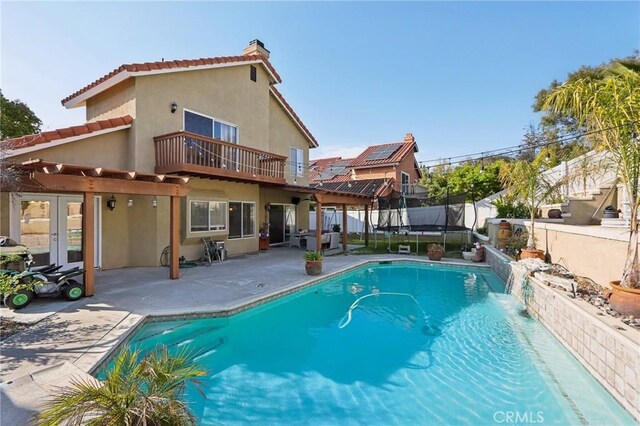 back of property with a fenced in pool, a fenced backyard, stucco siding, a patio, and a trampoline