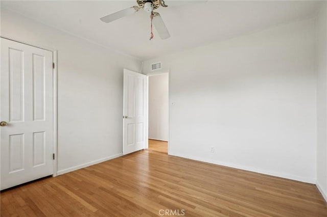 unfurnished bedroom featuring baseboards, a ceiling fan, light wood-style flooring, and visible vents