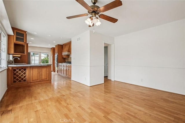 unfurnished living room featuring a sink, a ceiling fan, recessed lighting, and light wood-style flooring