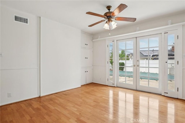 empty room featuring ceiling fan, french doors, light wood finished floors, and visible vents
