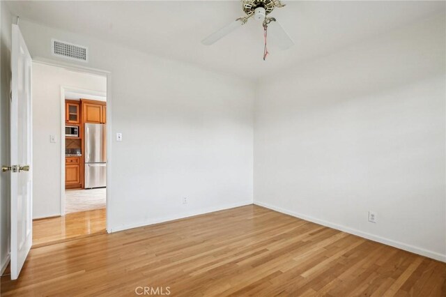 empty room featuring baseboards, visible vents, and light wood finished floors