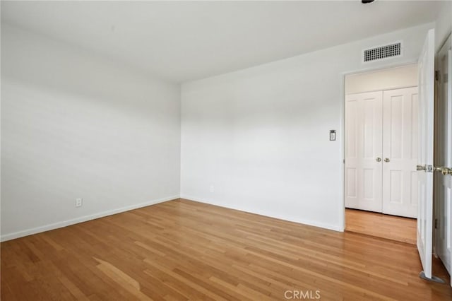 spare room featuring visible vents, light wood-style flooring, and baseboards