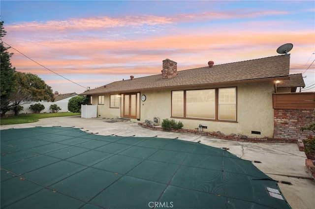 back of property featuring fence, stucco siding, a chimney, a fenced in pool, and a patio area