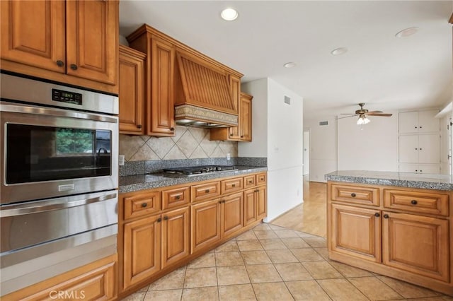 kitchen featuring custom exhaust hood, tasteful backsplash, a ceiling fan, appliances with stainless steel finishes, and a warming drawer
