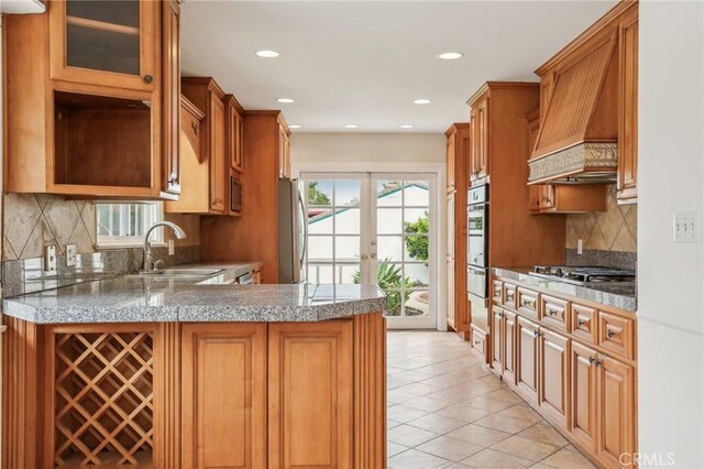 kitchen with a sink, premium range hood, stainless steel appliances, recessed lighting, and light tile patterned floors