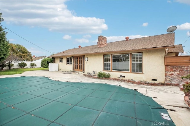 back of house featuring a chimney, a patio area, fence, a fenced in pool, and stucco siding