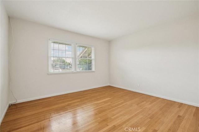 spare room featuring baseboards and light wood finished floors