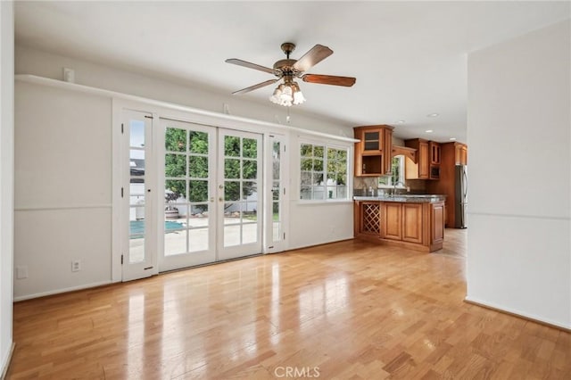 interior space featuring freestanding refrigerator, dark countertops, ceiling fan, brown cabinets, and french doors