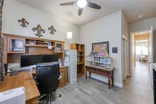 home office featuring light wood finished floors, baseboards, and a ceiling fan