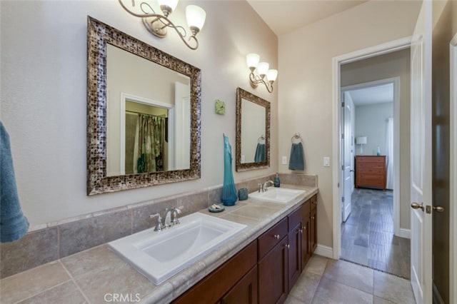full bath featuring a sink, tile patterned floors, double vanity, and a chandelier